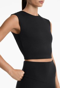 Top fitness cropped nero con scollatura rotonda e maniche a cappuccio, realizzato in tessuto elasticizzato. Presenta una superficie liscia e un design aderente.