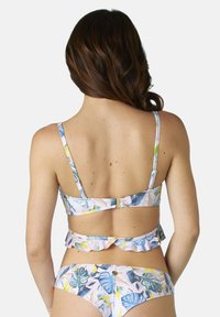 Top bikini floreale con spalline sottili, dettagli di ruffle sul retro e chiusura a gancio; colori pastello con motivi di foglie tropicali.