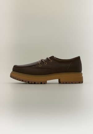 Chaussure marron à lacets avec semelle épaisse texturée couleur fauve et bout rond, montrée de profil sur un fond neutre.