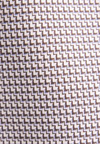 Textil mit einem Zickzackmuster in Braun und Hellblau auf weißem Hintergrund, mit einer gewobenen Textur und einem konsistenten geometrischen Design.