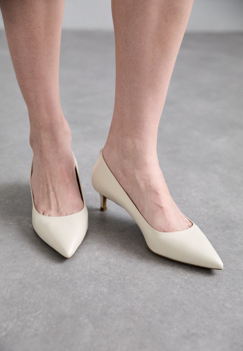 Beige terava varvaskingad, millel on lihtne disain, sile nahk ja peen stiletto konts, esitades minimalistlikku stiili.