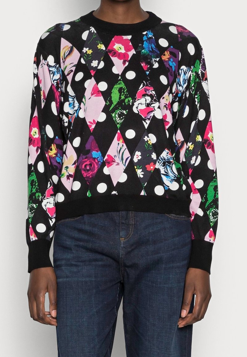 Sort sweater med diamantmønster og farverige blomsterprints samt prikker. Ribbede manschetter og kant. Båret med mørkeblå jeans.