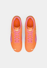 Orange Sneaker mit pinken Akzenten, mit einer strukturierten Oberseite, elongated Form und flachen Schnürsenkeln. PUMA Branding in der Nähe der Ferse und Zunge.