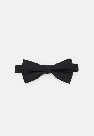 Nœud papillon noir en tissu lisse, présentant une forme classique avec un nœud central et une sangle ajustable. Design minimaliste, sans motifs.