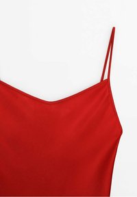 Haut caraco en satin rouge sans manches avec fines bretelles doubles et un léger décolleté en V sur fond blanc.