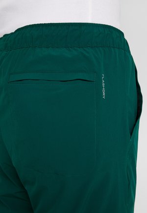 Mørkegrønne shorts med elastisk linning og en baglomme, med teksten "FLASHDRY" på sidesømmen.