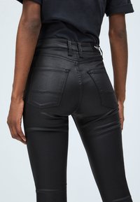 Svarta skinny jeans i denim med en slät textur, hög midja och två bakfickor. Har minimal sömnad och en strömlinjeformad silhuett.