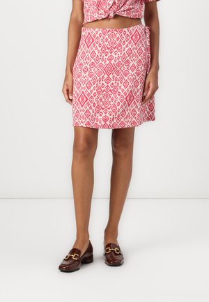 Ett rosa mønstrete omslagskjørt laget av lett stoff, med et diamantmønster. Sammen med blanke brune loafers med gullhardware.