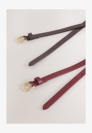 Dwa skórzane paski w ciemnobrązowym i bordowym kolorze, z złotymi sprzączkami, gładką teksturą oraz wieloma otworami do regulacji na pasku.