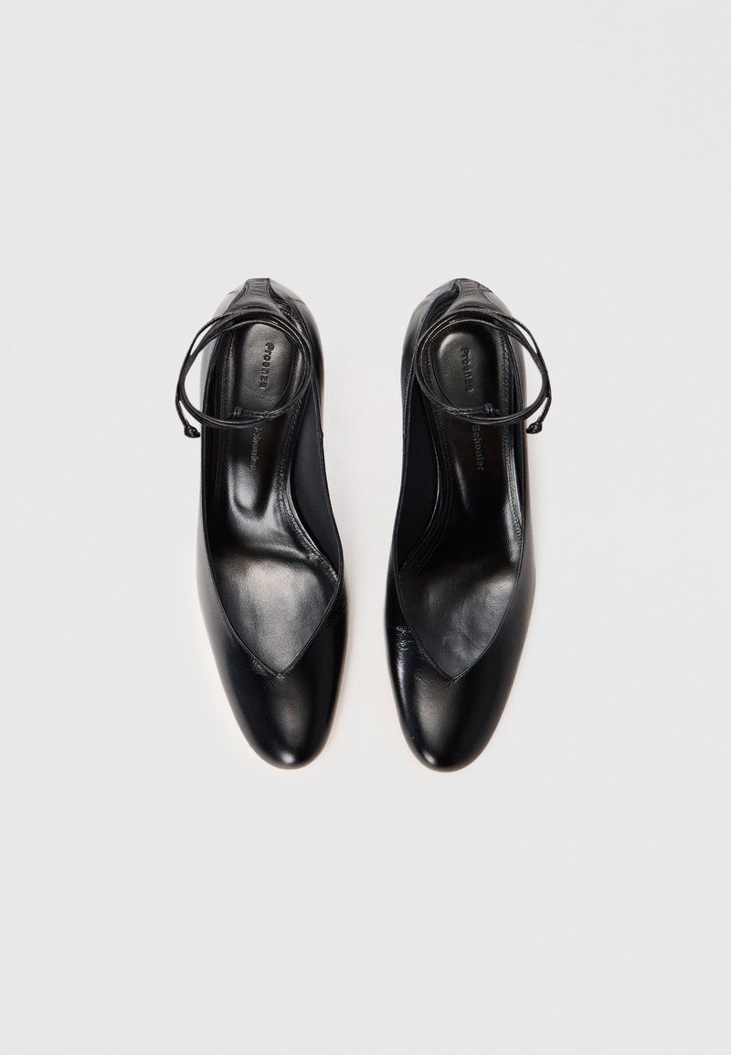 Schwarze Leder schuhe mit einer spitzen Zehe und einem ausgeschnittenen Design. Besitzt einen dünnen Schnürriemen um den Knöchel für einen sicheren Sitz. Glatte Textur.