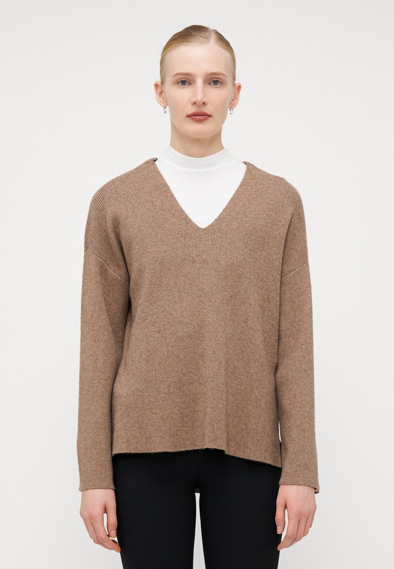 Brauner Strickpullover mit V-Ausschnitt, lockerer Passform und langen Ärmeln. Strukturierter Stoff mit einem Saum, der auf Hüfthöhe sitzt.