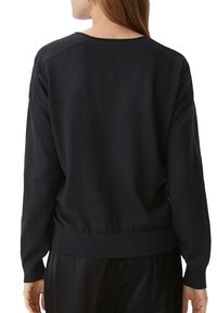 Zwart pullovertrui van zachte stof, met een ronde halslijn, geribbelde manchetten en een getailleerde taille, met een iets losse pasvorm.