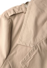 Lichtbeige trenchcoatstof, met een puntige kraag, schouderepauletten en nette stiksels. Gladde, lichte textiel.