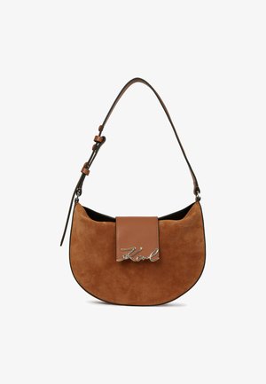 Rjava suprana torba s zaobljeno obliko, prilagodljivim trakom in svetlo rjavo usnjeno zanko z metalnim detajlom logotipa.