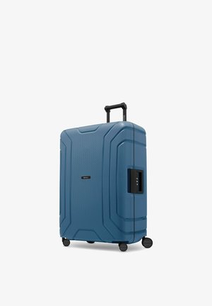 Valigia rigida blu con superficie testurizzata, manico nero retrattile, quattro ruote e lucchetto a combinazione integrato sul lato.