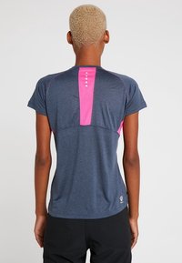 Camiseta atlética de manga corta en azul oscuro con panel de malla rosa en la parte trasera, que presenta cinco acentos en forma de botón blancos y un ajuste relajado.