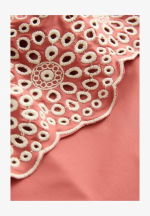 Material corai cu broderie albă complicată, care prezintă modele circulare și margini ondulate. Textură moale cu decupaje notabile.