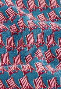 Blue fabric patterned with rows of small red and white striped beach chairs angled slightly to the right.