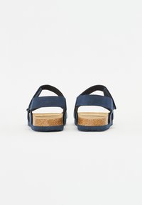 Marinblå sandaler med mockaläderremmar och korkfotbädd. Öppen bakdesign, justerbar vristrem, texturerad gummisula.