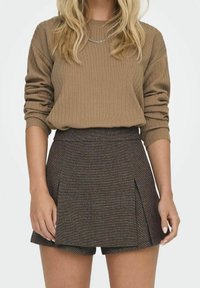 Brązowy sweter prążkowany z długimi rękawami, w połączeniu z dopasowanymi do talii brązowymi szortami z wełny w kratę. Teksturowany materiał, casualowy fason.