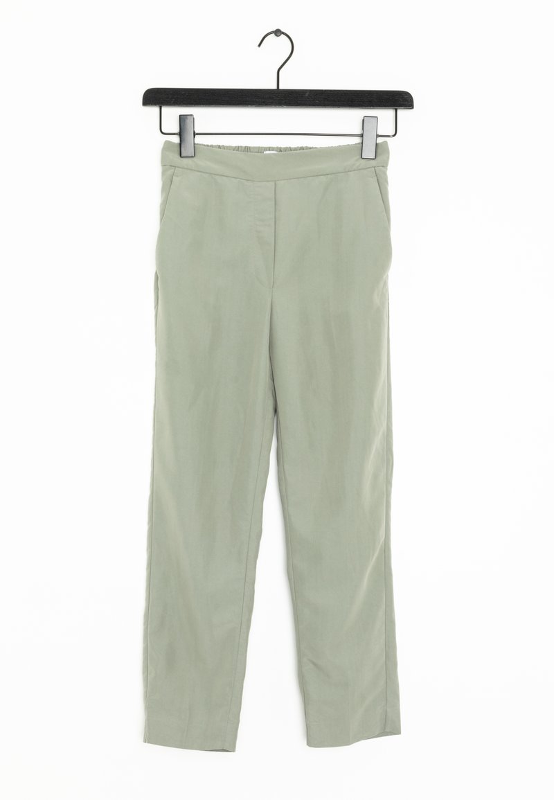 Pantalons vert clair en tissu lisse, dotés d'une taille élastique, de jambes droites et de poches latérales. Suspendus à un cintre noir.