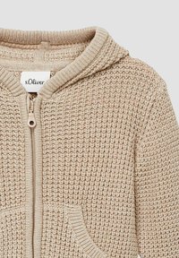 Beige gestrickter Hoodie mit Reißverschluss, strukturiertem Muster, gerippten Bündchen und zwei Fronttaschen. Das Etikett trägt die Aufschrift "s.Oliver."