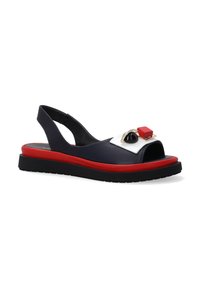 Slingback sandaal met een marineblauwe leren bovenkant, open teen en een contrasterende rode zool. Bevat decoratieve accenten in zwart en rood. Platte ontwerp.
