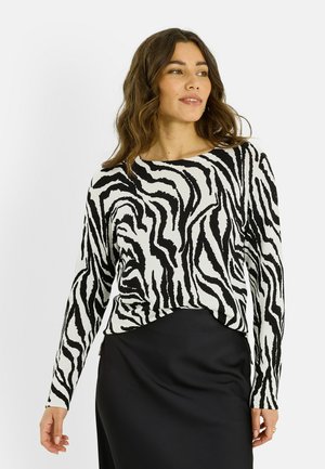 Haut à manches longues zébré noir et blanc en tissu doux, associé à une jupe noire lisse. Doté d'un col rond et d'une coupe régulière.