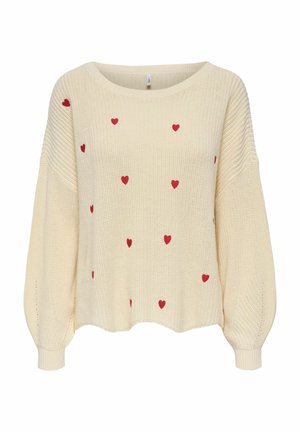 Pull en tricot crème avec de longues manches bouffantes et de petits motifs de cœurs rouges éparpillés sur le devant et les manches.