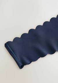 Laivansinisellä lehtikankaalla, sileällä pinnalla ja huolitellulla reunoilla, joka sopii erilaisiin sovelluksiin, kuten muotiin tai sisustukseen.