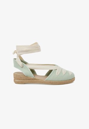 Sandale espadrille vert clair avec une semelle en jute, dotée de brides en coton croisées et d'un dessus texturé pour une meilleure adhérence.