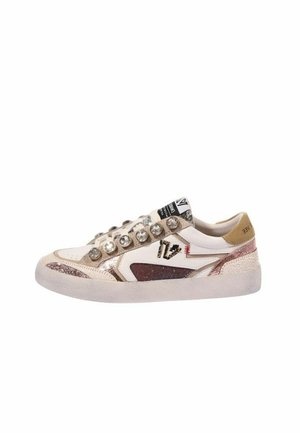 Sneaker low-top in pelle bianca e beige, con accenti rosa metallizzati, grandi pietre decorative trasparenti al posto dei lacci e logo nero ricamato sul lato.