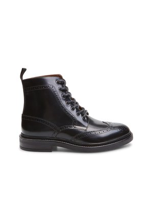 Botín de cuero negro a la altura del tobillo con detalles de brogue, puntera redonda, diseño de cordones, lengüeta y tacón apilado. Textura suave con acabado brillante.