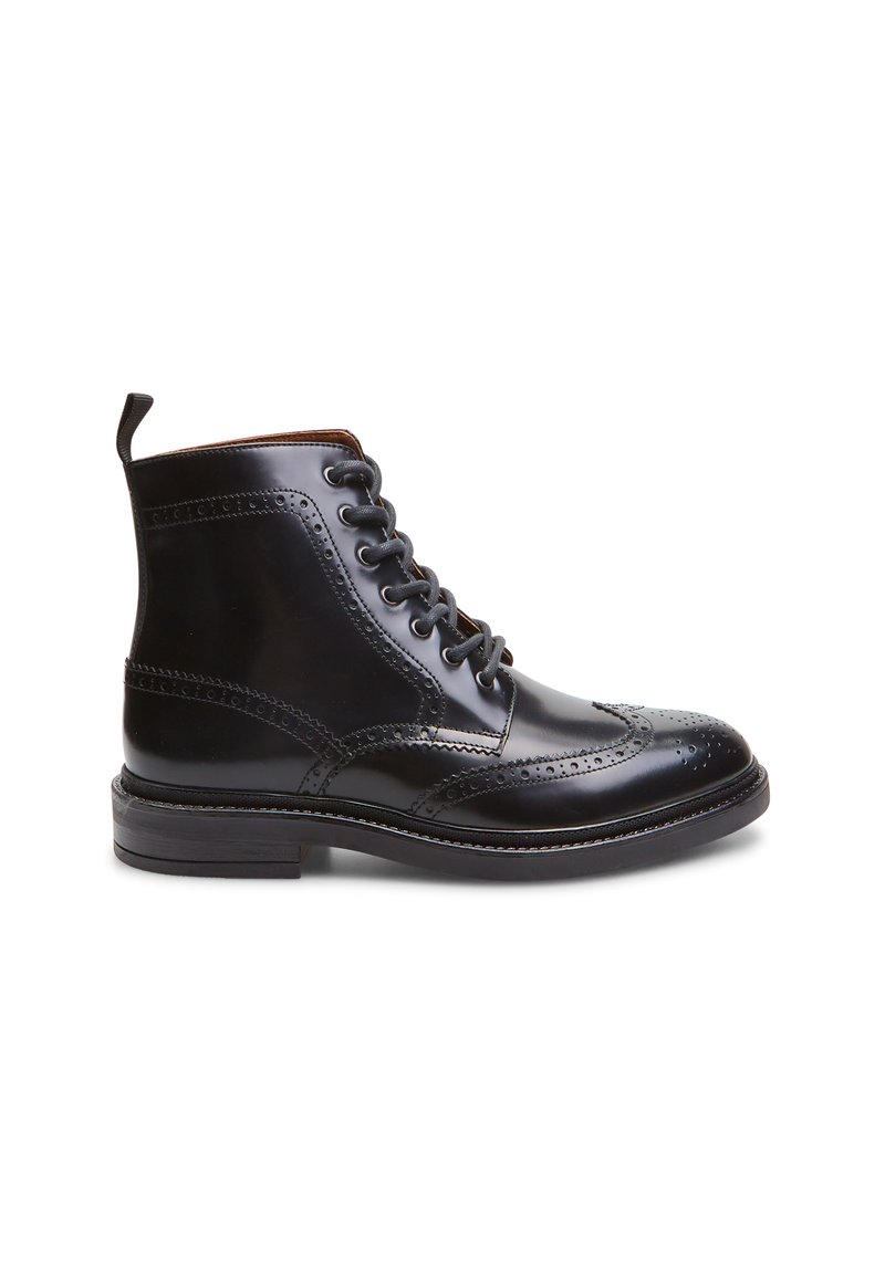 Botín de cuero negro a la altura del tobillo con detalles de brogue, puntera redonda, diseño de cordones, lengüeta y tacón apilado. Textura suave con acabado brillante.