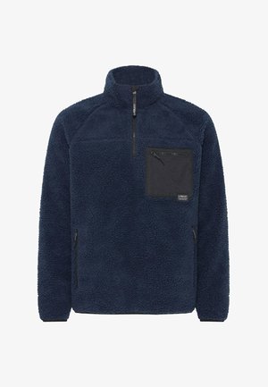 Mørkeblå fleece-pullover med høj krave, lynlås foran og sort lomme. Har en blød overflade og sidelommer med lynlås.
