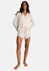 Lightweight, short-sleeve, button-up pajama set in soft beige fabric; shorts feature lace trim; elastic waistband with pink drawstring.