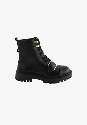 Juodos odinės kulkšninių botų nėriniai priekyje, dekoratyvinis šonas su sagtimi ir storas gumos padas su reljefiniu raštu.