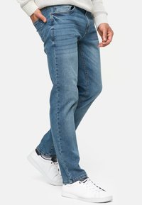 Lichtblauwe denim jeans met een slim fit, voorzien van vijf zakken, subtiele vervaging en gestikte details. Gecombineerd met witte sneakers.