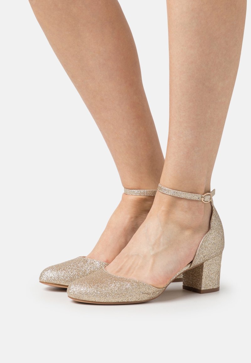 Chaussures à paillettes dorées, talon bas avec bride à la cheville. Bout arrondi et surface texturée ; talon bloc offrant une bonne stabilité. Convient pour les occasions formelles.