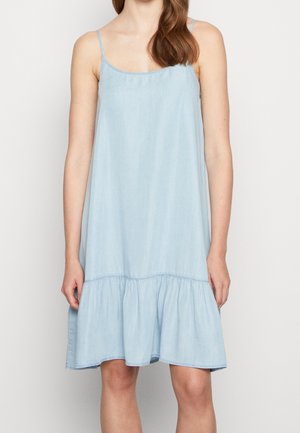 Valkoinen, hihaton mekko denim-kankaasta, jossa on leveä, röyhelöinen helma. Sisältää ympyräkaula-aukon ja ohuet olkaimet.