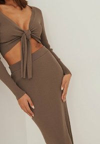Ensemble deux pièces rayé marron comprenant un crop top noué à manches longues et une jupe taille haute, le tout en matière douce et texturée.
