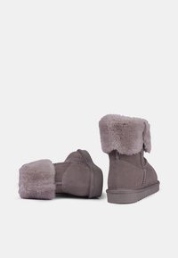Stivaletti alla caviglia in suede grigio con una morbida rifinitura in pelliccia, caratterizzati da una punta rotonda, suola piatta e dettagli di cucitura a contrasto.