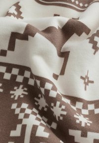 gebreide stof met een geometrisch patroon in bruin en wit, met een zachte textuur en een lichte rek, in een gevouwen positie.