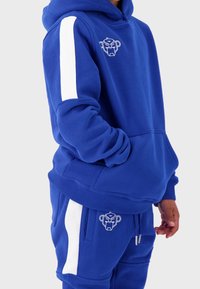 Blue hooded sweatshirt with white stripes on sleeves, featuring a front pocket and a logo on the chest. Soft fabric with a relaxed fit.