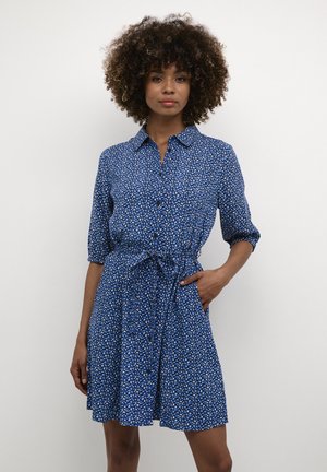 Blaues Blumenkleid mit durchgeknöpfter Vorderseite, Kragen, Dreiviertelärmeln, Taillengürtel und schwingendem Rock. Leichtes Gewebe mit kleinen Mustern.