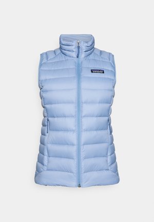 Šviesiai mėlynas pūstas liemenė su aukštu apykakliu, užtrauktuku priekyje ir šoninėmis kišenėmis. Turi siūtas detales ir mažą logotipą ant krūtinės.