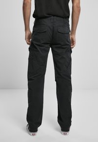 Schwarze Cargo-Hosen aus strapazierfähigem Stoff, mit großen Seitentaschen, lässiger Passform und verstärkten Nähten. Einfaches Design, ohne Muster.