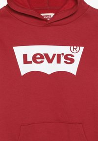 Felpa rossa realizzata in misto cotone, con un grande logo bianco di Levi's sul davanti. Il design include una tasca a marsupio e un cappuccio con cordino.