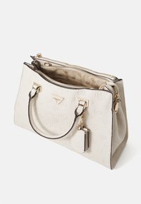 Bolso de mano texturizado en color beige con herrajes dorados, compartimentos de doble cremallera, una pequeña etiqueta colgante y asas más cortas para llevar en la mano.