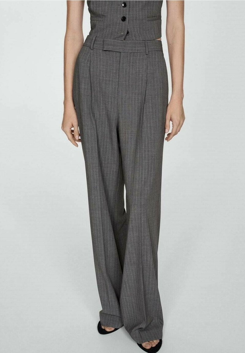 Femme portant un pantalon gris à fines rayures taille haute, jambes larges, avec un gilet sans manches assorti et des chaussures noires à bout ouvert.